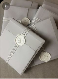 four white envelopes with ribbons tied around them and some buttons on the top one