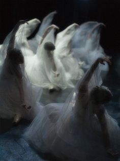 several people dressed in white are floating on the water with their arms spread out and hands extended