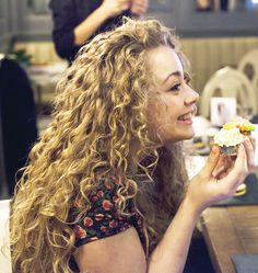 a woman sitting at a table with a cupcake in her hand