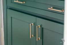 a green cabinet with brass handles and knobs