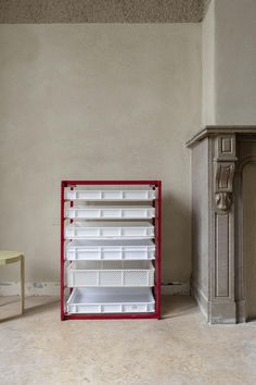 a red and white shelf sitting next to a fireplace in a room with beige walls