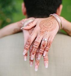 a man and woman with henna tattoos on their hands are holding onto each other