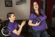 two people in purple shirts are playing with remotes and smiling while standing next to each other