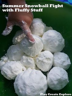 a green bowl filled with white snowballs next to a person's hand pointing at it