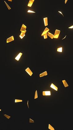 many pieces of yellow paper floating in the air on a black background with light coming from them