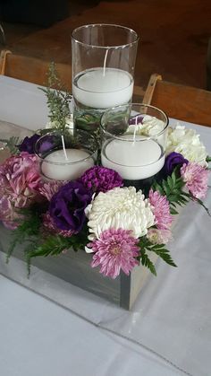 flowers and candles on a table with white cloth