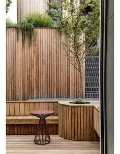 a wooden bench sitting on top of a wooden deck next to a tree and planter