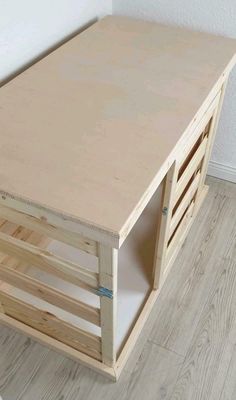 a wooden crate sitting on top of a hard wood floor next to a white wall