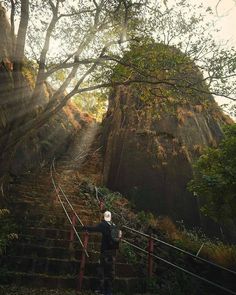 a man walking up some stairs in front of a mountain with trees on the other side