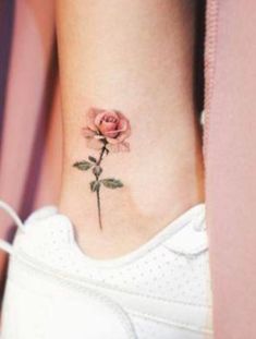 a small pink rose tattoo on the side of a woman's ankle and foot