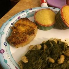 a plate topped with meat, greens and cupcakes next to muffins