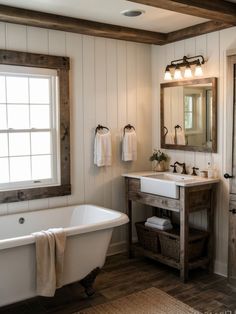 a white bath tub sitting under a bathroom mirror next to a wooden sink counter top