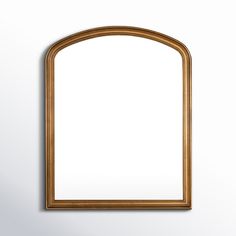 an arch shaped mirror hanging on the wall with a white back ground and light wood frame