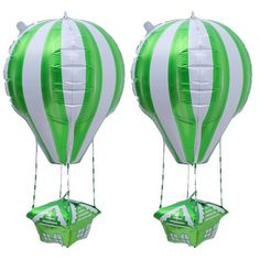 two green and white hot air balloons in the shape of boats floating on top of each other