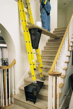 a man standing on top of a yellow ladder next to a set of stairs with luggage