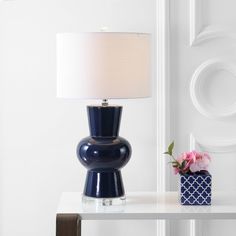 a blue lamp sitting on top of a table next to a vase with pink flowers