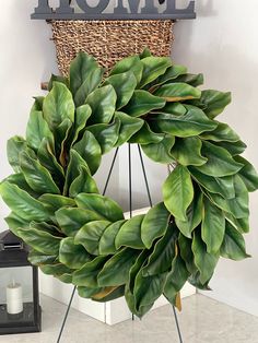 a large green wreath sitting on top of a wooden stand next to a sign that says home