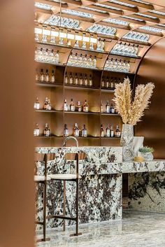 a marble counter top sitting next to a wooden shelf filled with bottles and vases