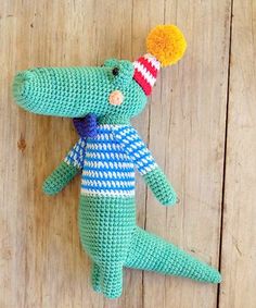 a crocheted stuffed alligator laying on top of a wooden floor