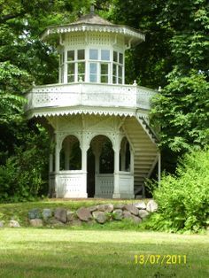 a white gazebo sitting in the middle of a lush green park