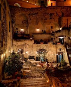 an old building with tables and chairs in the courtyard at night, lit up by candles