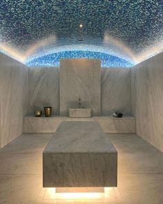 an empty room with white marble walls and blue lights on the ceiling is lit up by recessed lighting