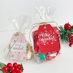 two christmas gift bags with tags on them sitting next to other holiday gifts and decorations