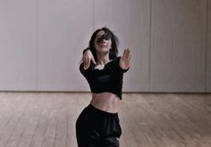 a woman standing on top of a wooden floor holding her hands up in the air