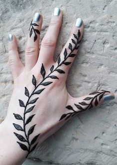 a woman's hand with black leaves on it