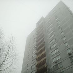 a very tall building with lots of windows on it's side in the fog