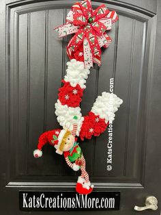 a christmas wreath hanging on the front door with santa clause and candy canes attached to it