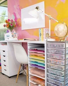 a desk with many drawers and a lamp on it in front of a colorful wall