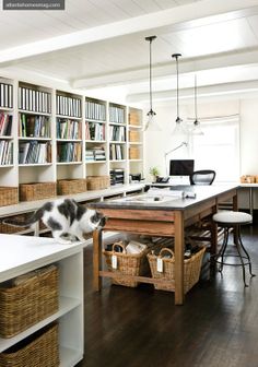 a cat is sitting on top of a table in the middle of a room with many bookshelves