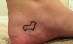 a small dog tattoo on the foot of a person's left foot, which has a black outline of a dog