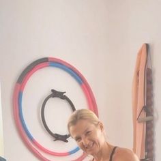 a woman standing in front of a wall with three rings on the wall behind her