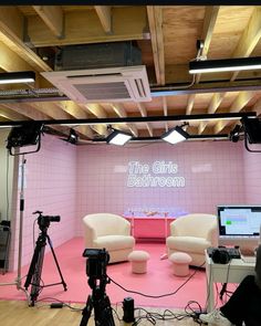 a pink room with two white chairs and a television set in front of the camera