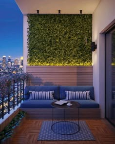 an outdoor living area with blue couches and plants on the wall, overlooking city lights