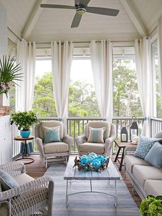 a living room with two couches and chairs on the front porch, covered in white curtains