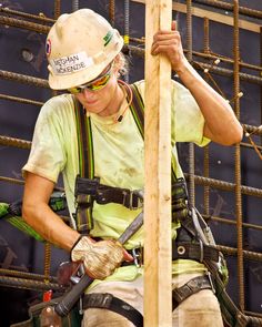 a man in safety gear working on a wooden pole