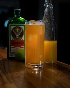 an orange juice in a glass next to a bottle