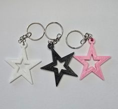 three star shaped key chains are shown on a white surface, one is pink and the other is black