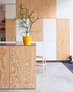 a yellow vase filled with green plants on top of a wooden counter in a kitchen