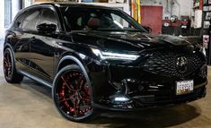 a black suv parked in a garage with red rims on the front and sides