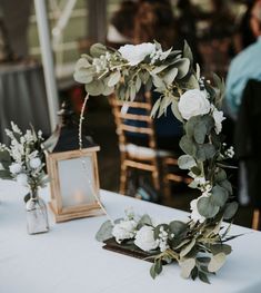 the table is set up with white flowers and greenery