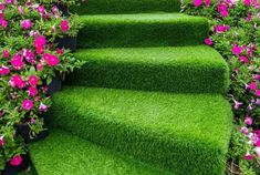 a set of stairs made out of artificial grass with pink flowers growing on each step