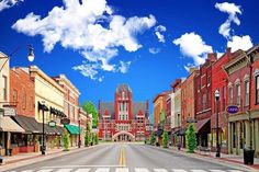 an empty city street with buildings on both sides and clouds in the sky above it