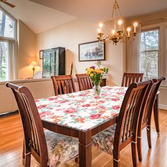 a dining room table with flowers on it in front of two windows and a chandelier