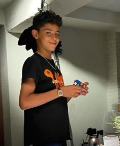 a young boy standing in front of a table holding a bottle and looking at the camera