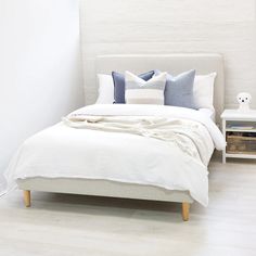 a bed with white linens and blue pillows