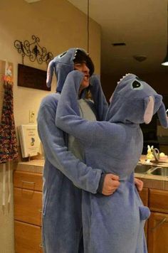 a woman in a blue elephant costume hugging a man wearing a gray oneshirt